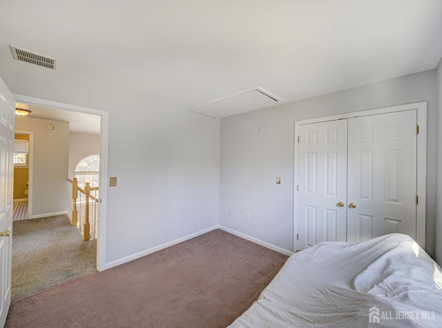 carpeted bedroom featuring attic access, baseboards, and a closet