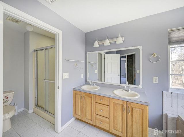 full bath with tile patterned floors, a shower stall, double vanity, toilet, and baseboards