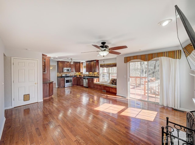 unfurnished living room with ceiling fan, hardwood / wood-style floors, and baseboards