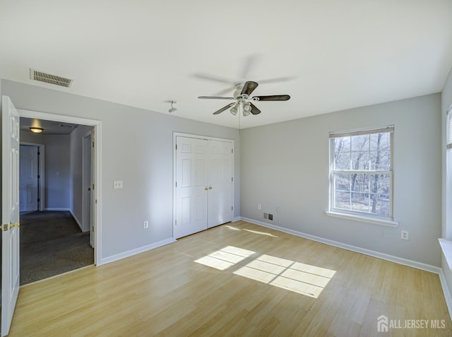 unfurnished bedroom featuring light wood-style flooring, baseboards, a closet, and a ceiling fan