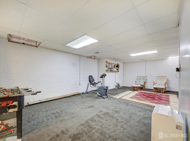 exercise area featuring a drop ceiling, carpet flooring, and concrete block wall