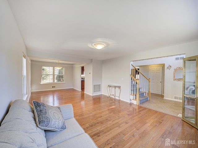 living area featuring wood finished floors, stairs, and baseboards