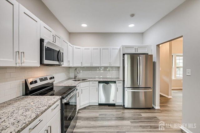 kitchen featuring light stone counters, appliances with stainless steel finishes, sink, and white cabinets