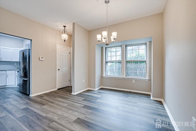 unfurnished dining area featuring hardwood / wood-style floors and a chandelier