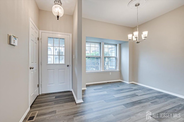 foyer entrance featuring hardwood / wood-style flooring, a wealth of natural light, and a notable chandelier