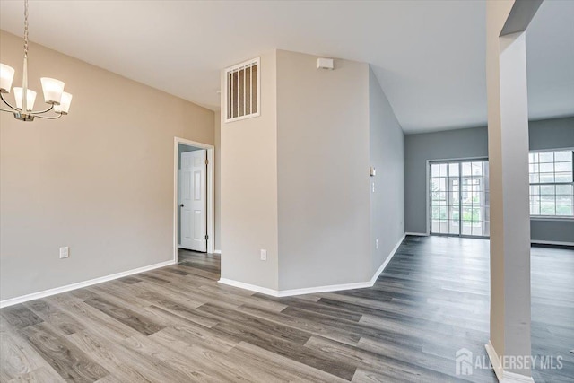 spare room with hardwood / wood-style flooring and a chandelier