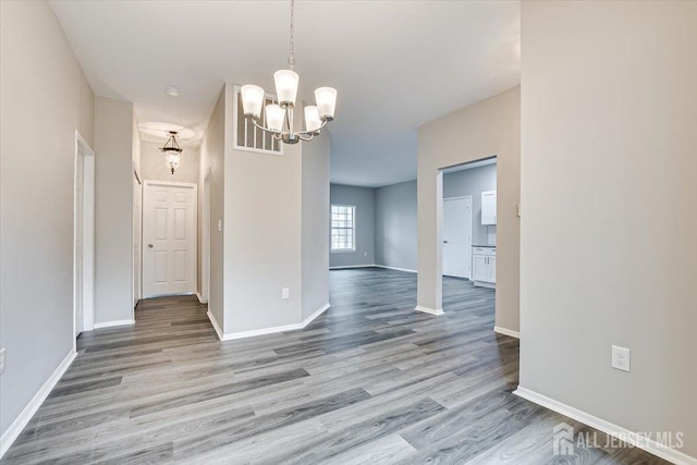 unfurnished room with a chandelier and light hardwood / wood-style flooring