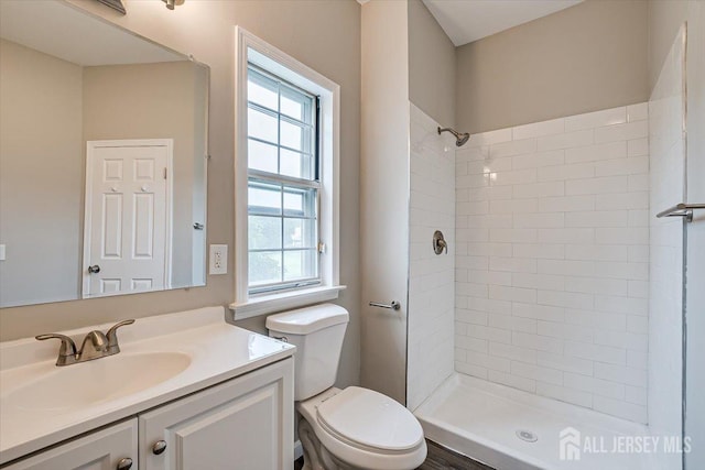 bathroom with tiled shower, vanity, and toilet