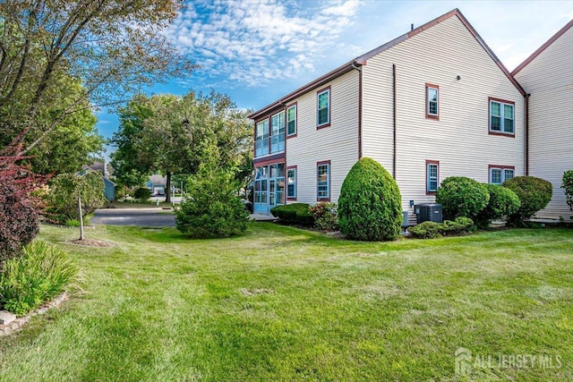 view of side of property featuring a yard and central air condition unit