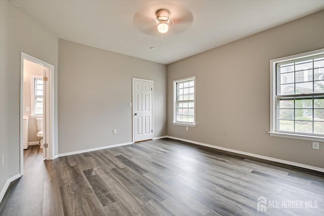 empty room with ceiling fan and dark hardwood / wood-style flooring