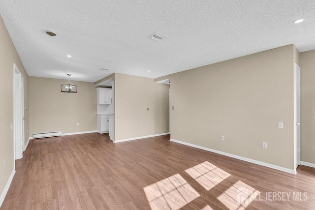 162 Providence Way, Monroe, NJ 08831 - unfurnished living room with a baseboard heating unit, baseboards, a textured ceiling, and light wood finished floors