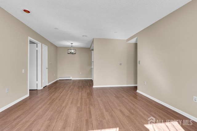 unfurnished room featuring baseboards, baseboard heating, and wood finished floors