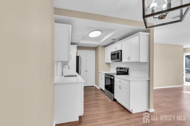 kitchen featuring stainless steel appliances, a sink, light countertops, and light wood-style floors