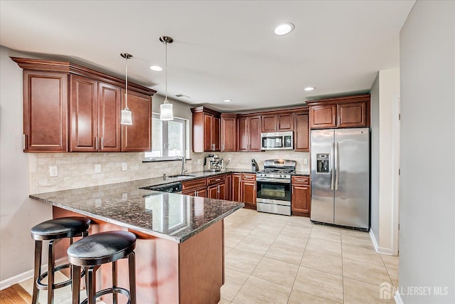 1142 Warren St, Roselle, NJ 07203 - kitchen with stainless steel appliances, decorative backsplash, a peninsula, dark stone countertops, and pendant lighting