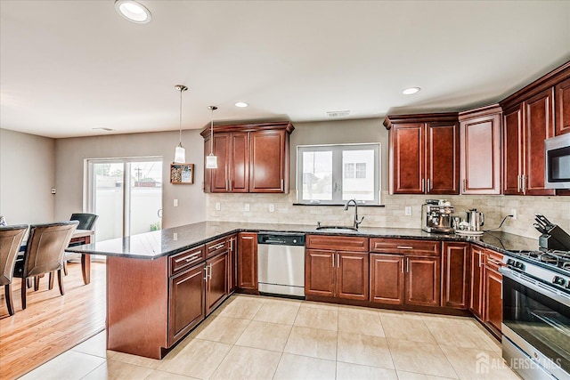 1142 Warren St, Roselle, NJ 07203 - kitchen featuring appliances with stainless steel finishes, a peninsula, tasteful backsplash, dark stone counters, and hanging light fixtures