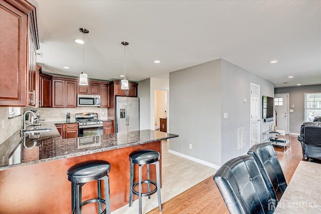 1142 Warren St, Roselle, NJ 07203 - kitchen with stainless steel appliances, open floor plan, a peninsula, dark stone countertops, and light wood-type flooring