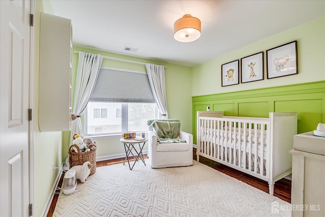 1142 Warren St, Roselle, NJ 07203 - bedroom with a nursery area, wood finished floors, and a wainscoted wall