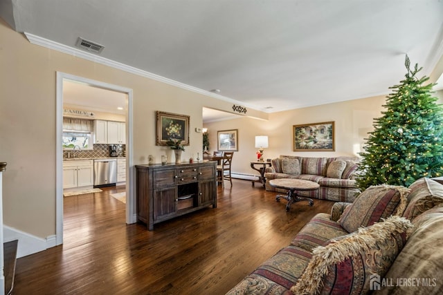 living room featuring crown molding, baseboard heating, sink, and dark wood-type flooring