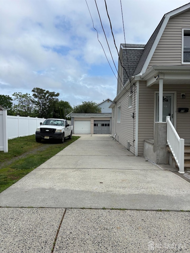 view of side of property featuring roof with shingles, fence, an outdoor structure, a gambrel roof, and a garage