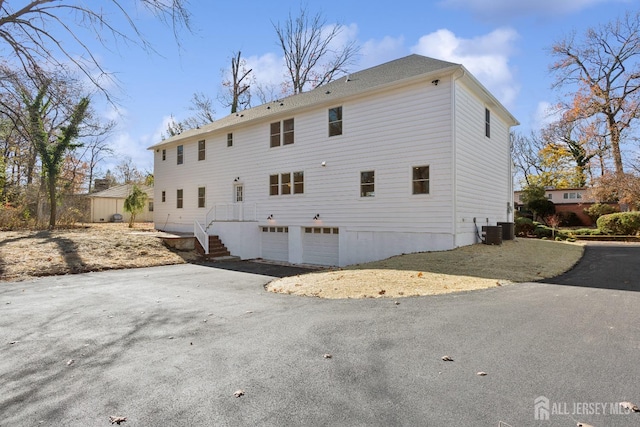 rear view of house with a garage and central AC unit