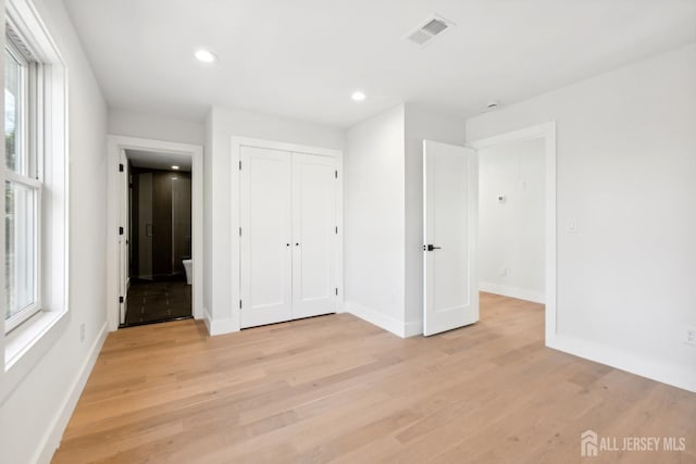 unfurnished bedroom with light hardwood / wood-style flooring and a closet