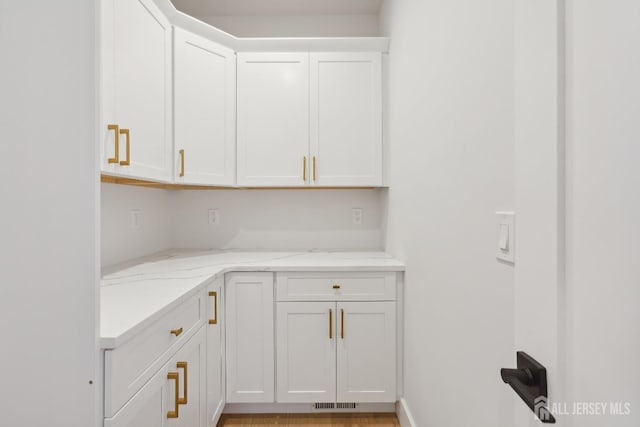 interior space with white cabinetry and light stone countertops