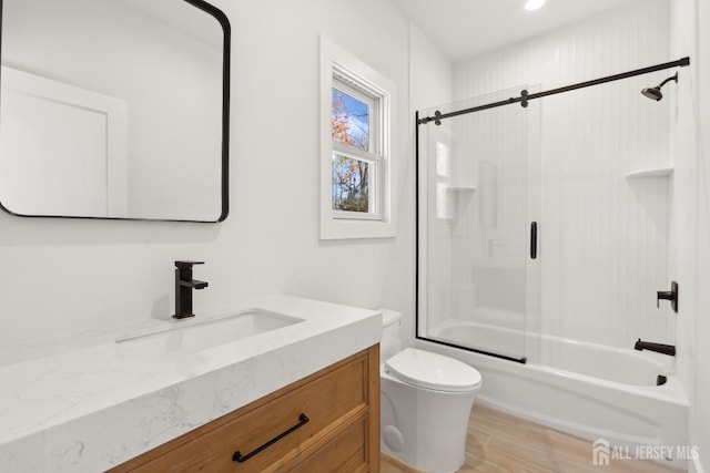 full bathroom featuring vanity, wood-type flooring, shower / bath combination with glass door, and toilet