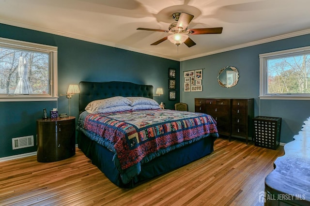 bedroom with multiple windows, visible vents, and wood finished floors