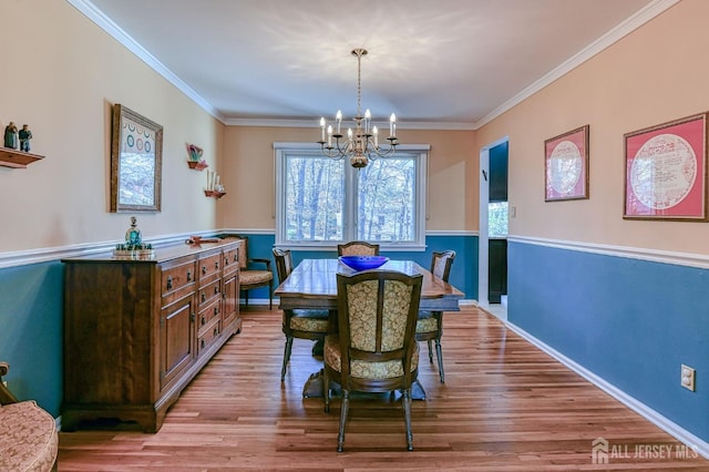 dining room with a notable chandelier, crown molding, baseboards, and wood finished floors