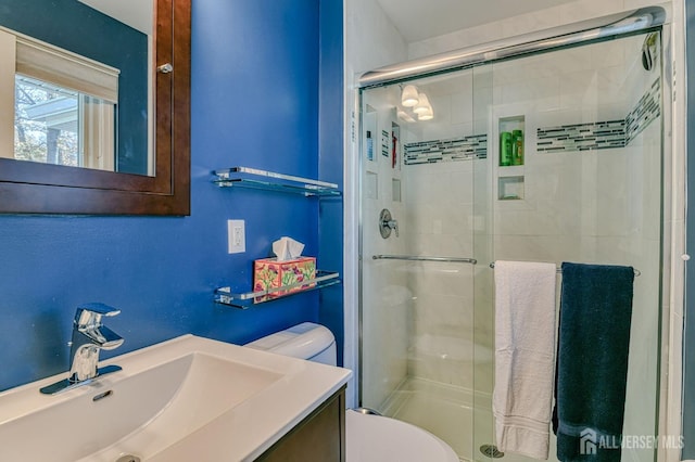 bathroom with toilet, a shower stall, and vanity