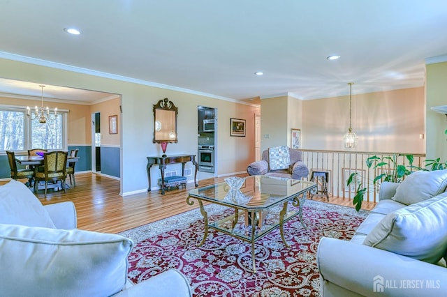 living area featuring crown molding, a wainscoted wall, wood finished floors, and a notable chandelier