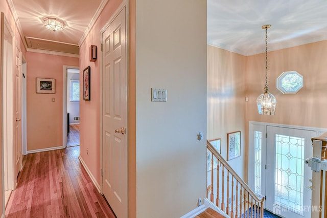 hall featuring a notable chandelier, wood finished floors, an upstairs landing, baseboards, and ornamental molding