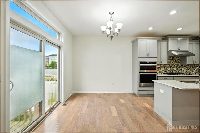 30 Clover Ln, Monroe, NJ 08831 - kitchen featuring under cabinet range hood, gray cabinetry, double oven, a chandelier, and light wood finished floors