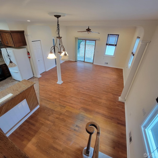 unfurnished living room with visible vents, a ceiling fan, crown molding, light wood finished floors, and baseboards