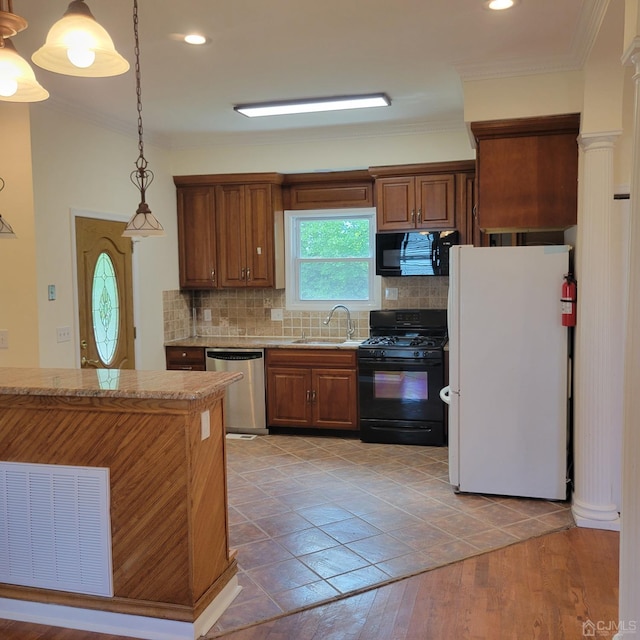 kitchen with sink, decorative backsplash, hanging light fixtures, light stone counters, and black appliances