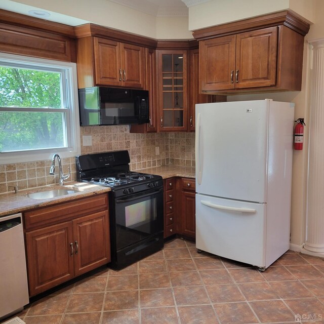 kitchen featuring tile patterned floors, sink, light stone counters, decorative backsplash, and black appliances