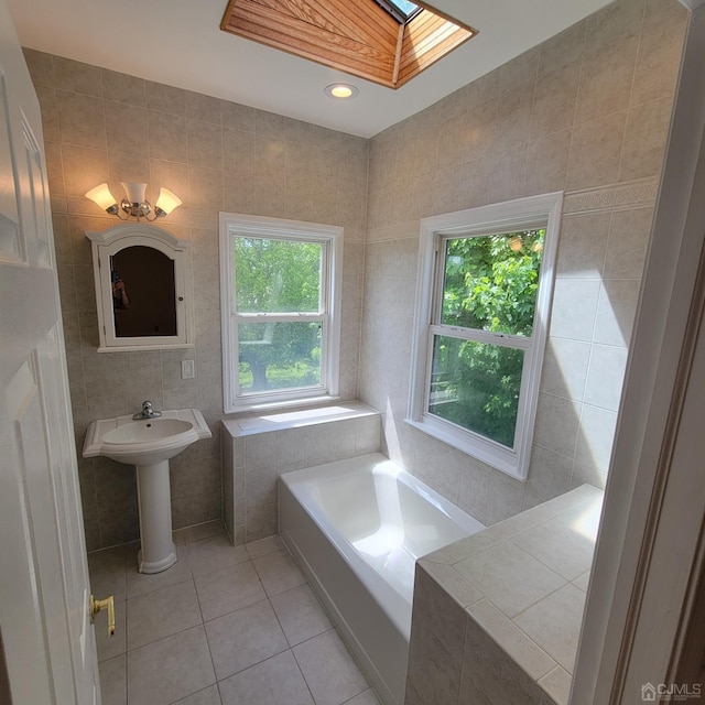 bathroom featuring tile patterned floors, a skylight, a bathtub, and tile walls