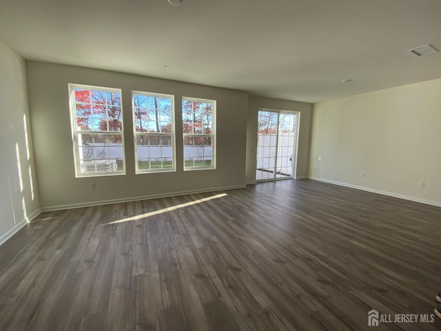 unfurnished living room featuring dark wood finished floors, baseboards, and visible vents