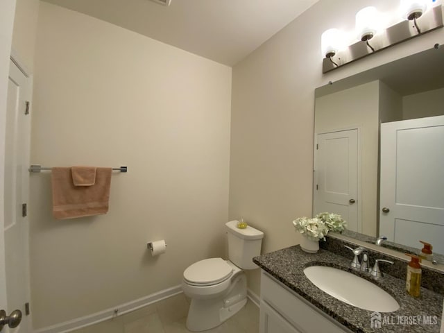 half bathroom with tile patterned floors, baseboards, toilet, and vanity