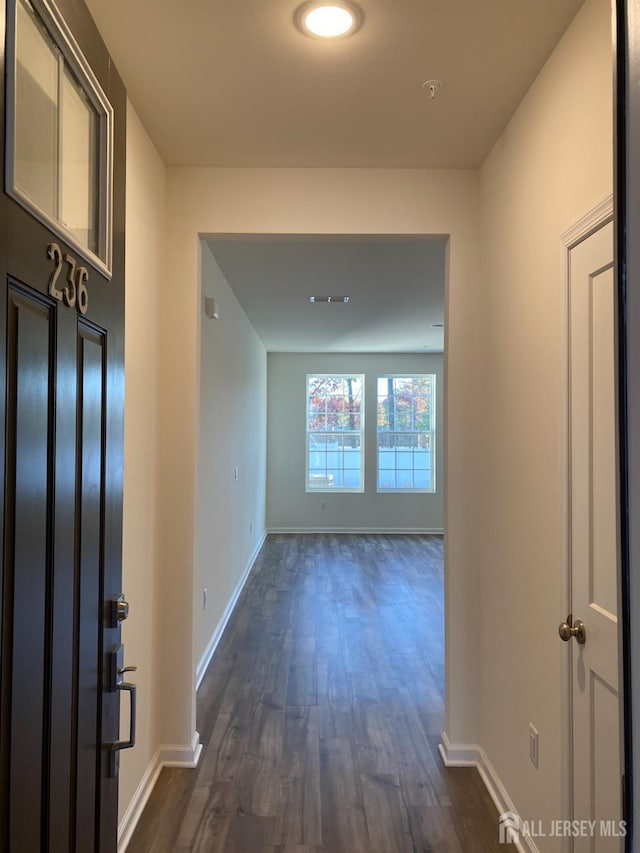 hallway featuring dark wood-type flooring and baseboards