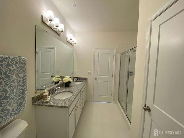 bathroom with double vanity, a stall shower, toilet, and a sink