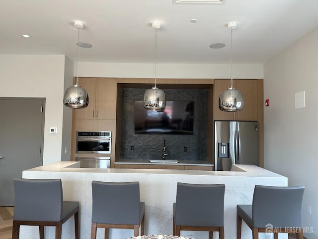 kitchen with a breakfast bar, decorative backsplash, stainless steel fridge with ice dispenser, and a sink