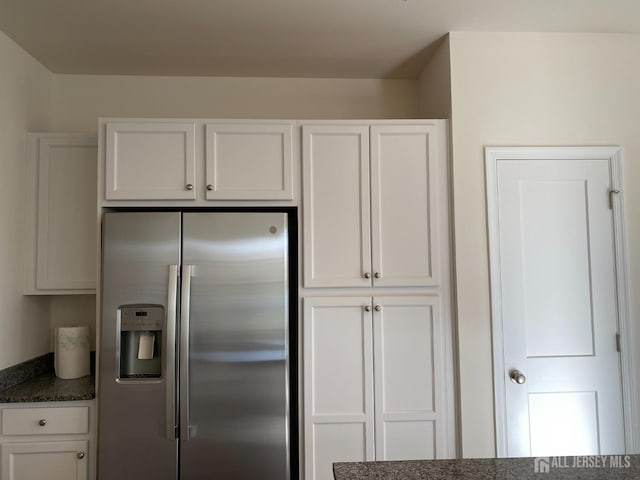 kitchen with dark stone counters, white cabinets, and stainless steel refrigerator with ice dispenser