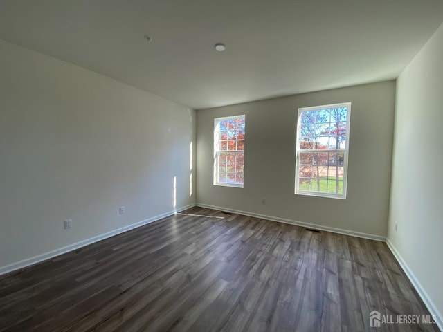 empty room with dark wood finished floors and baseboards