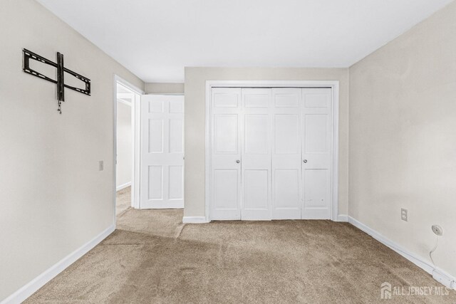 unfurnished bedroom featuring light carpet and a closet