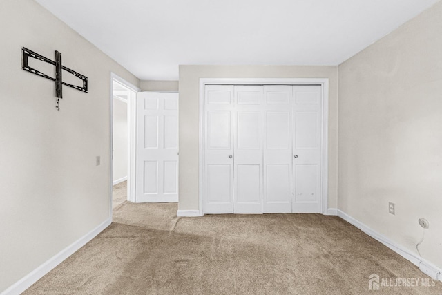 unfurnished bedroom with a closet, carpet flooring, and baseboards