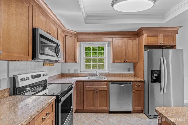 kitchen with sink, stainless steel appliances, a raised ceiling, decorative backsplash, and ornamental molding