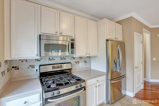 4215 Falston Cir Unit 15, Old Bridge, NJ 08857 - kitchen featuring appliances with stainless steel finishes, light countertops, ornamental molding, tasteful backsplash, and white cabinetry