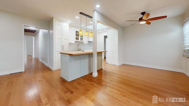 496 Calvert Rd, North Brunswick, NJ 08902 - kitchen featuring white cabinets, ceiling fan, light wood-style flooring, glass insert cabinets, and tasteful backsplash