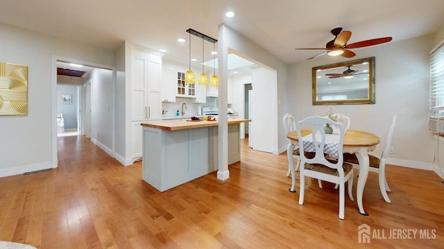 496 Calvert Rd, North Brunswick, NJ 08902 - kitchen with butcher block counters, white cabinets, glass insert cabinets, light wood finished floors, and a ceiling fan